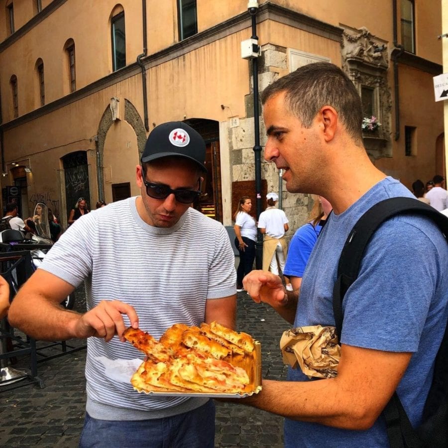 A Secret Food Tour Rome guide explains Roman pizza as an attendee samples a slice.